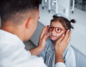 cute little girl getting glasses from eye doctor