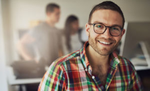 young man smiling wearing glasses